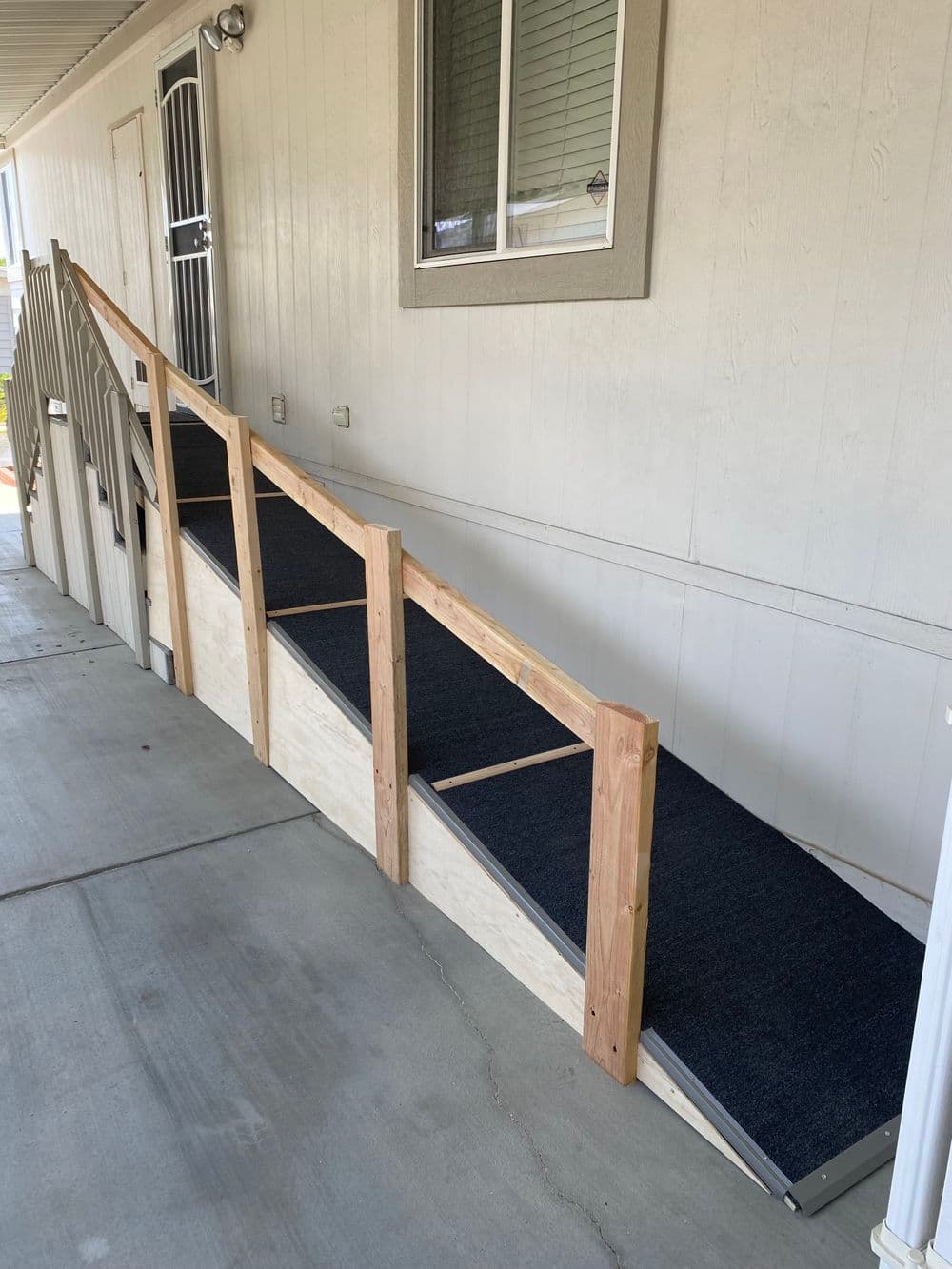 Accessible wooden ramp leading to a door, featuring non-slip surface and handrails.