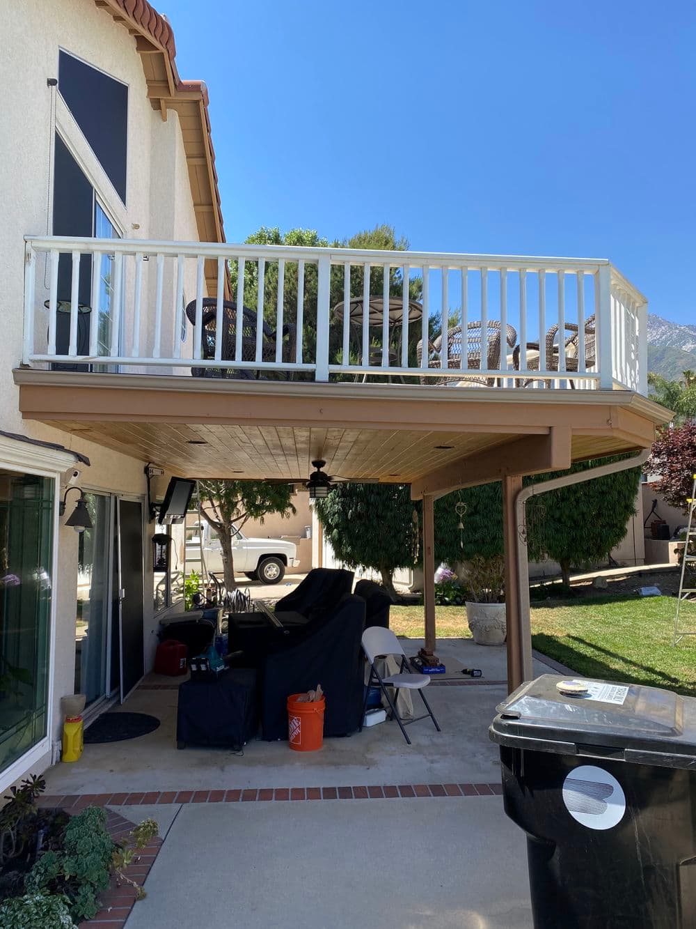 Two-story house with a covered balcony, outdoor furniture, and a grassy yard.