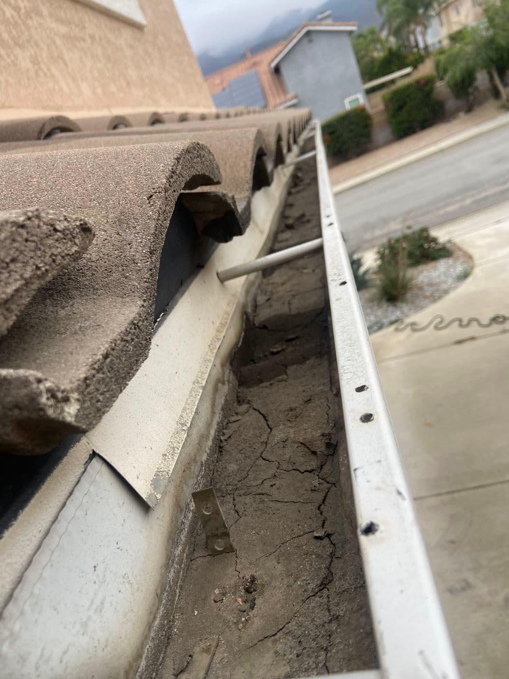 Dirty gutter with debris and cracks, showing potential home maintenance issues.