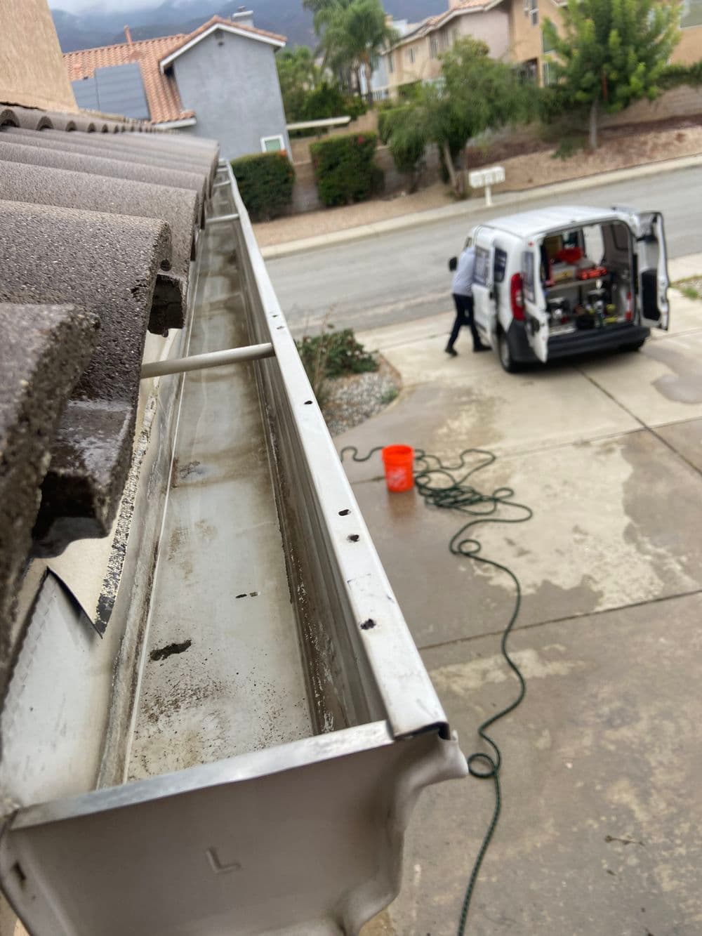 Gutter cleaning service in action, with workers and equipment visible in a residential area.