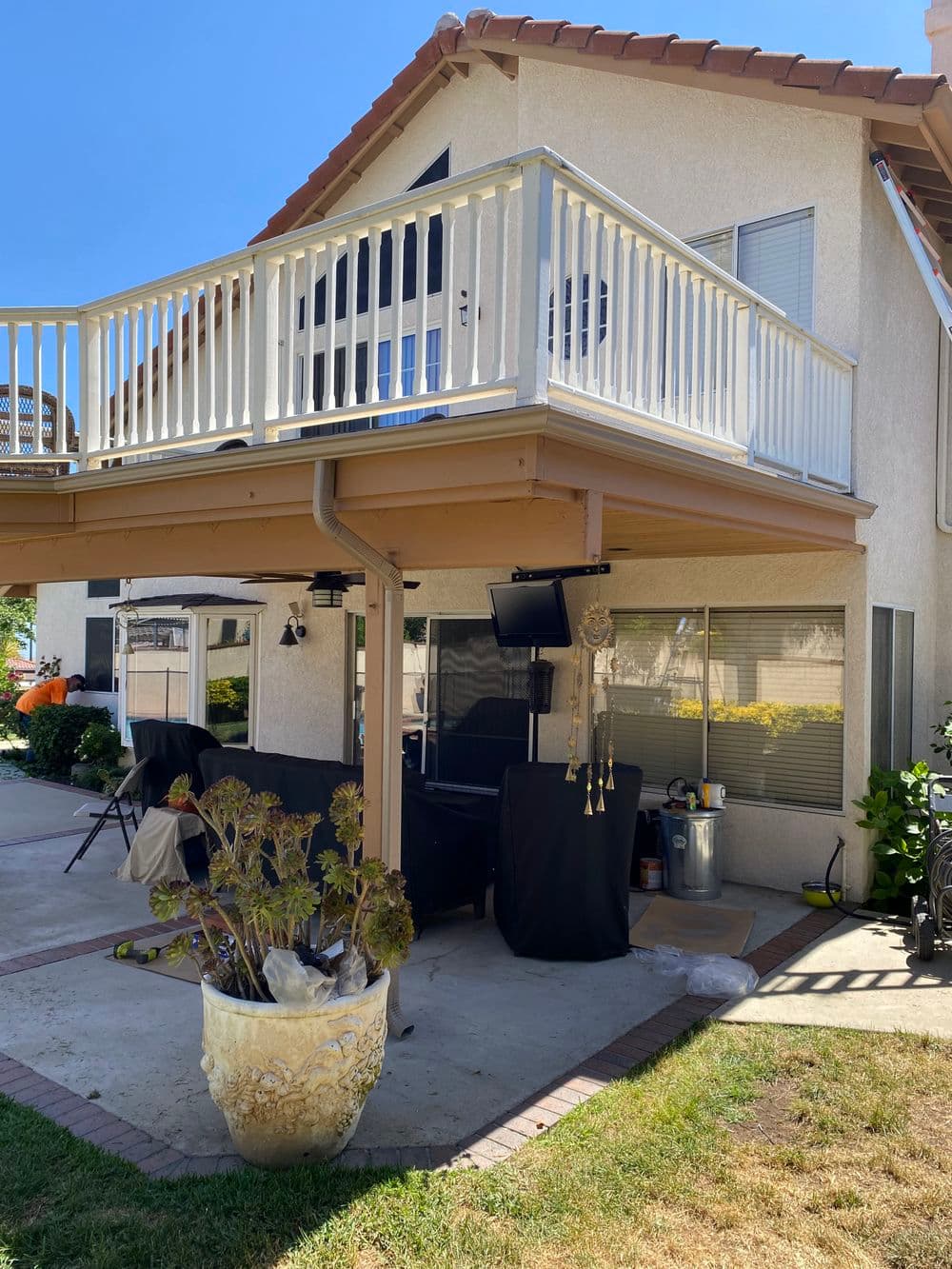 Multi-level home with a balcony and patio, featuring outdoor furniture and a plant.