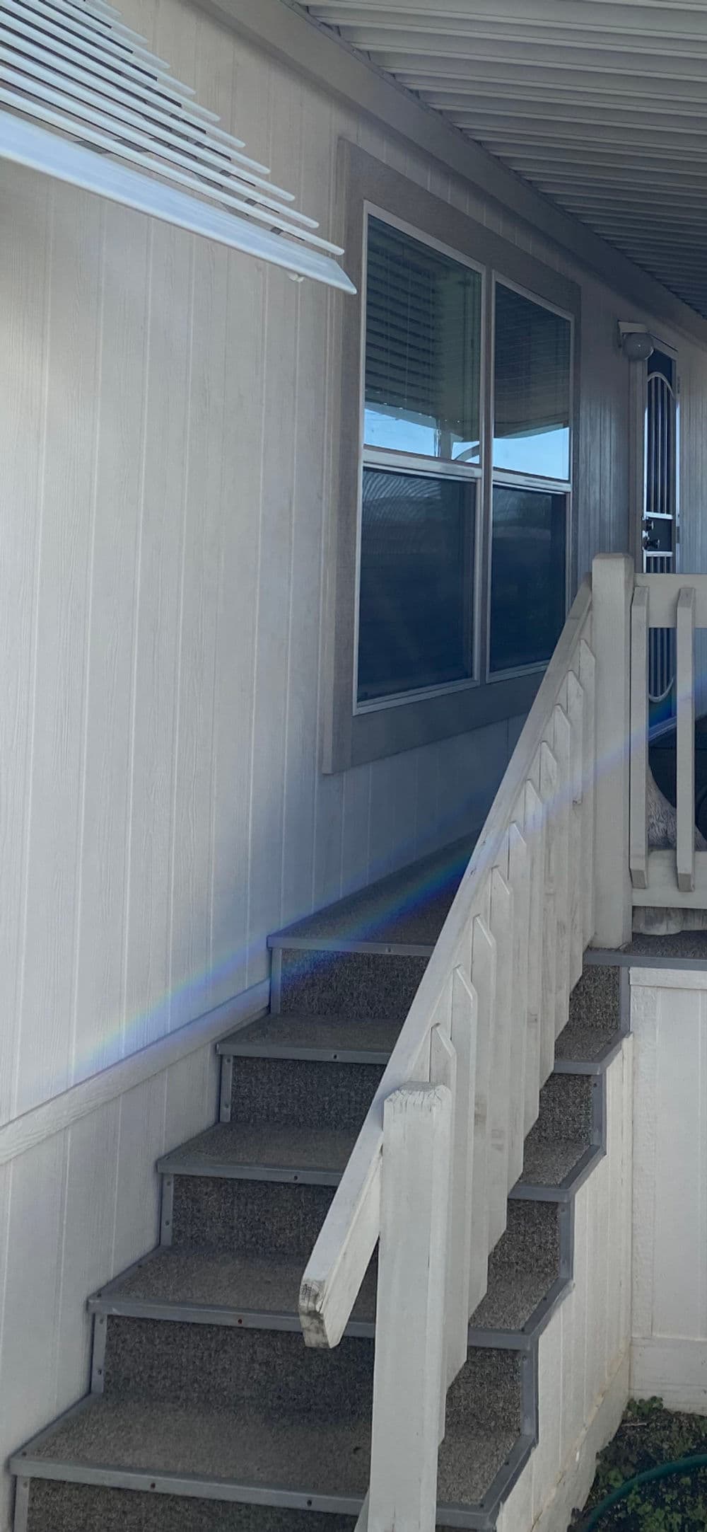 White stairway leading to a home entrance with windows and modern trim details.